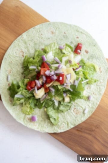 Vibrant Mediterranean Chicken Wrap 8 lettuce in wrap topped with red onion, roasted red pepper, and artichoke hearts