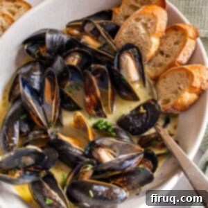 Mussels Infused with White Wine 11 Steamed mussels in a serving bowl filled with white wine sauce and crostini on the side.