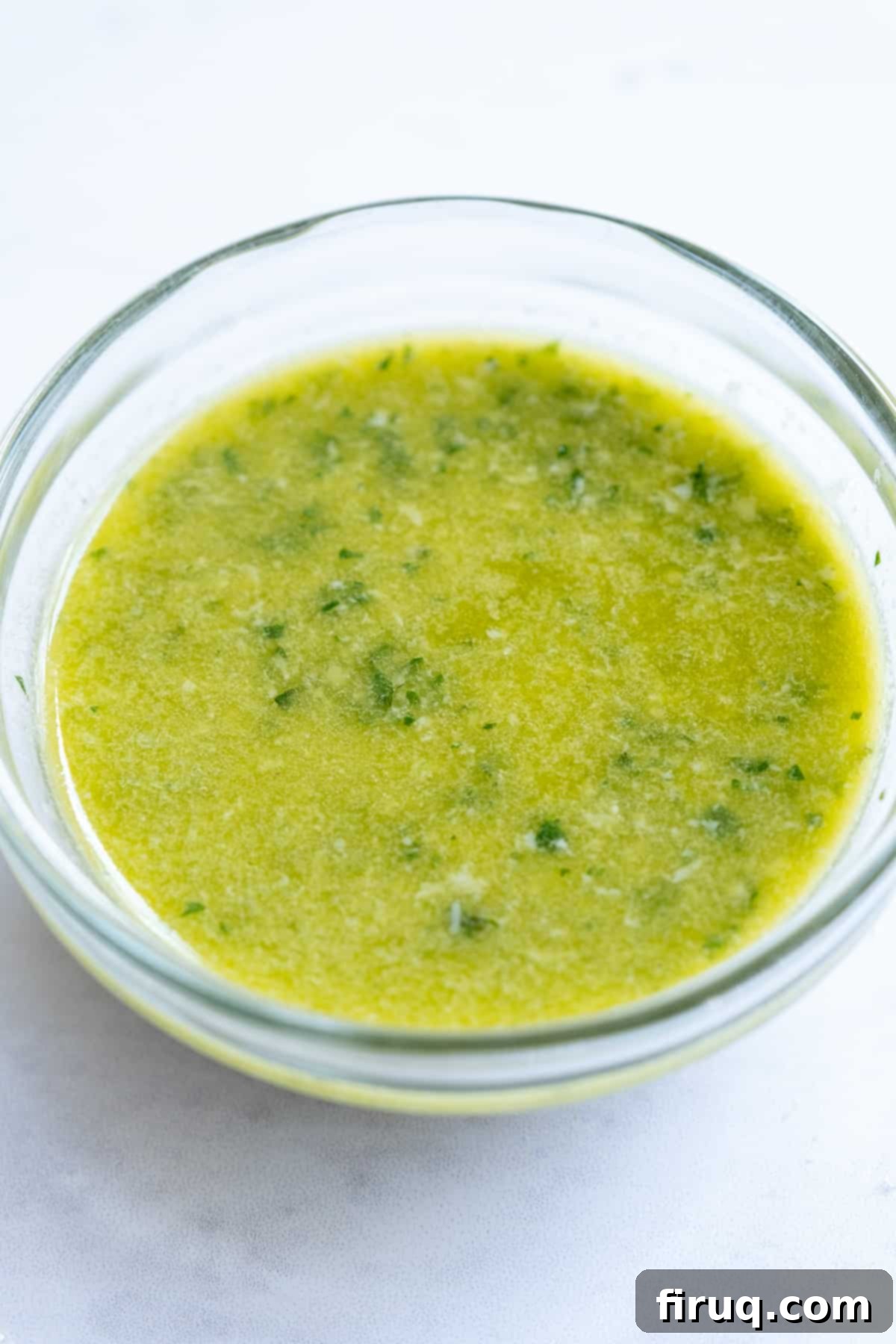 Zesty Basil-Lemon Dressing 2 freshly made lemon basil vinaigrette in a clear glass bottle, garnished with lemon slices and basil leaves.