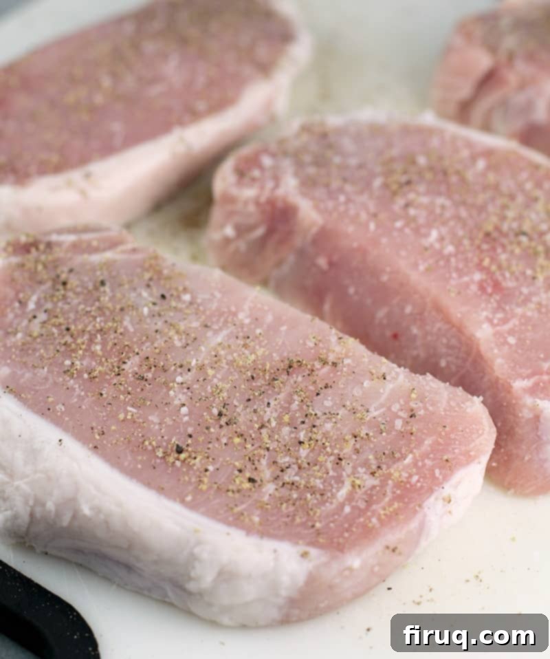 Hearty Pork Chop and Cornbread Bake 4 uncooked boneless loin pork on a white cutting board to show seasoning