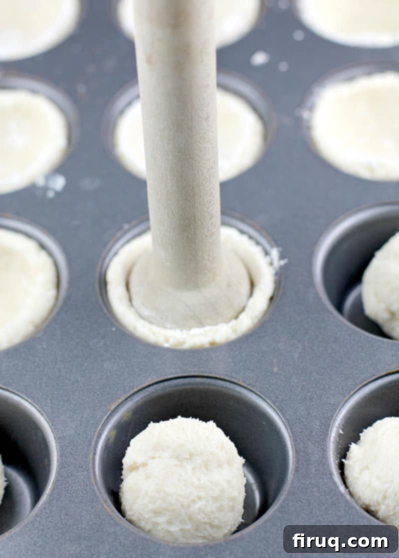 Velvet Cherry Cookie Tarts 5 Wood tamper pressing down the cream cheese cookie dough into the mini muffin tin