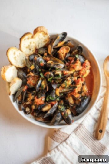 Christmas Eve's Seven Fishes Feast 5 Mussels Fra Diavolo with crusty Italian bread in a serving bowl.