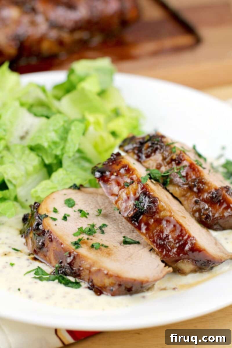 Bourbon-Glazed Pork Medallions with Zesty Mustard Sauce 2 sliced pork medallions with bourbon glaze, on white serving plate with salad
