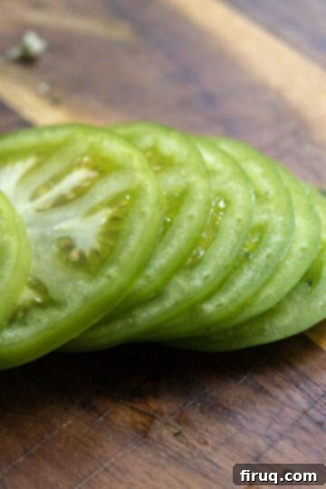 Crispy Italian Fried Green Tomatoes 4 Perfectly sliced green tomatoes on a cutting board, ready for breading.