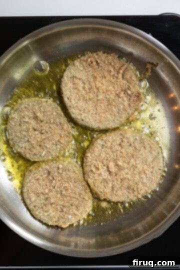 Crispy Italian Fried Green Tomatoes 7 Green tomatoes frying in hot olive oil in a non-stick pan, turning golden brown.