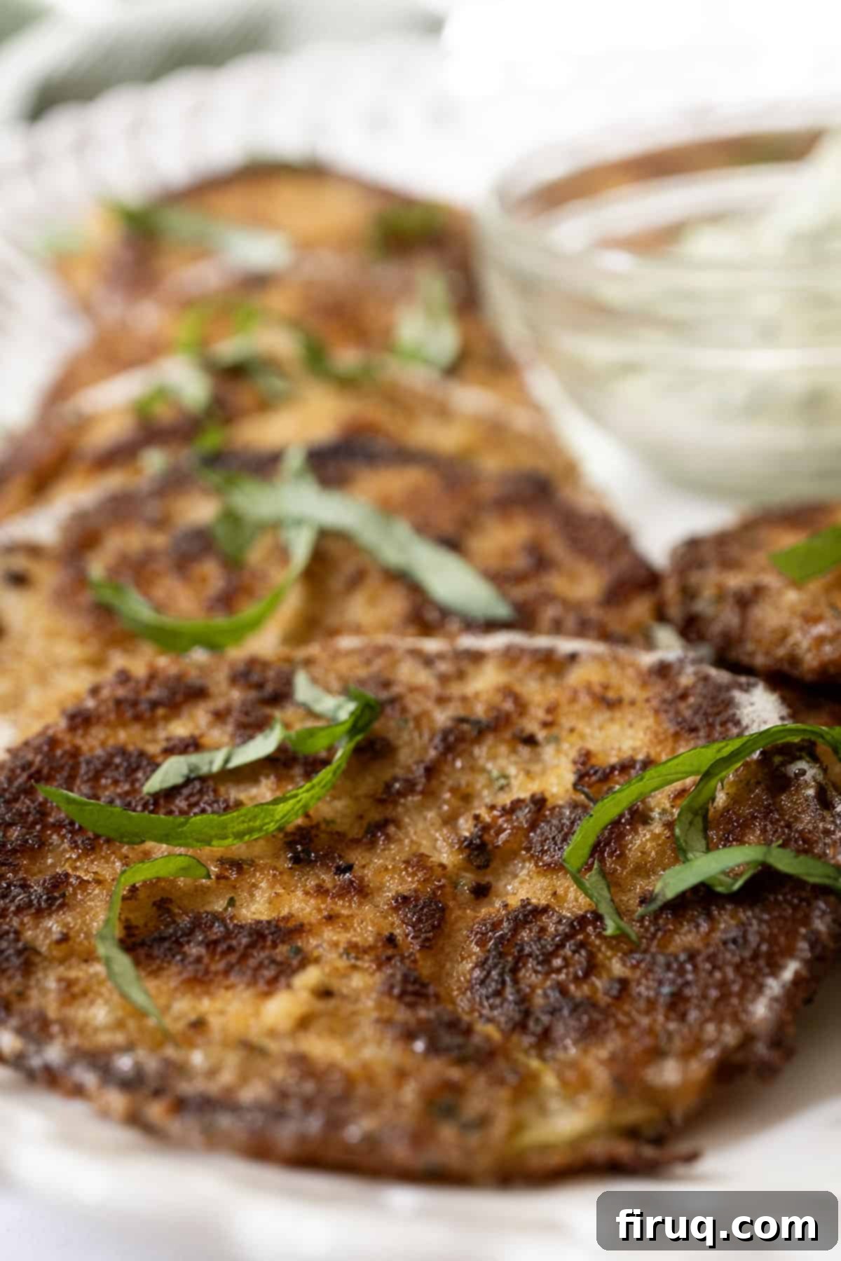 Crispy Italian Fried Green Tomatoes 9 Close-up of crispy Italian fried green tomatoes with a dollop of garlic basil aioli, garnished with fresh basil leaves.
