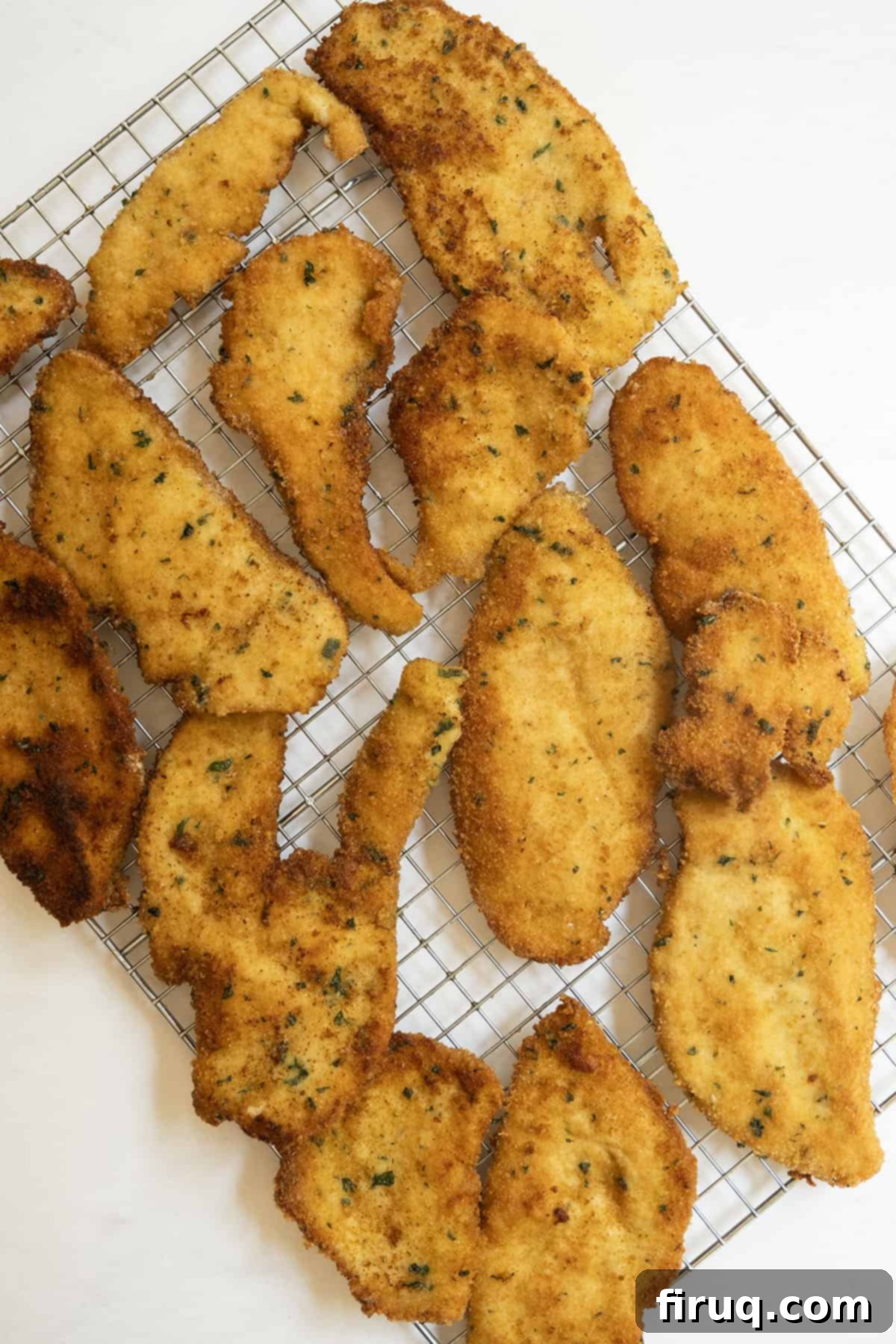 Crispy Golden Italian Chicken Cutlets 12 Crispy Italian chicken cutlets cooling on a wire rack over a baking sheet, ensuring maximum crispness.