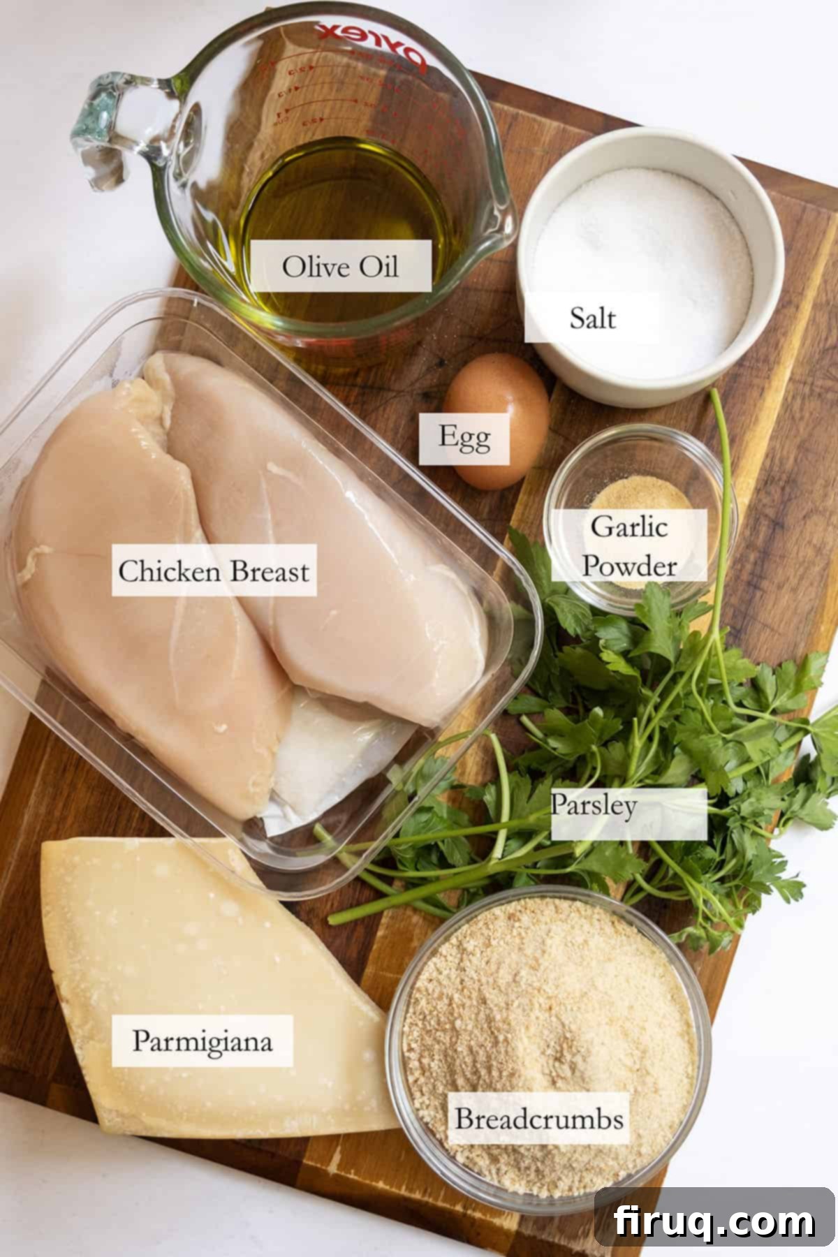 Crispy Golden Italian Chicken Cutlets 3 A selection of fresh ingredients including chicken breast, eggs, breadcrumbs, parsley, and olive oil, laid out for an Italian chicken cutlet recipe.