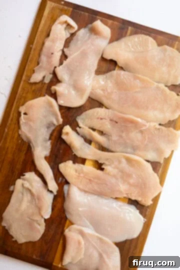 Crispy Golden Italian Chicken Cutlets 6 Thinly sliced chicken breast laid out on a cutting board, ready for pounding or breading.