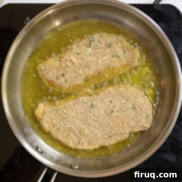 Crispy Golden Italian Chicken Cutlets 10 Several chicken cutlets frying in a pan of hot olive oil, sizzling to a golden crisp.