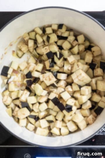 Tangy Eggplant Caponata 7 Chopped eggplant browning in a pan with other ingredients, softening before tomatoes are added to the Caponata.
