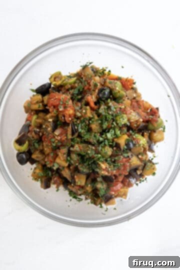 Tangy Eggplant Caponata 10 Freshly made Eggplant Caponata garnished with vibrant chopped parsley, ready to be served.