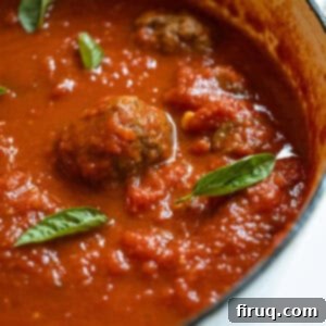 Grandma's Traditional Sunday Gravy 13 Sunday sauce with meatballs and sausage in a pot.