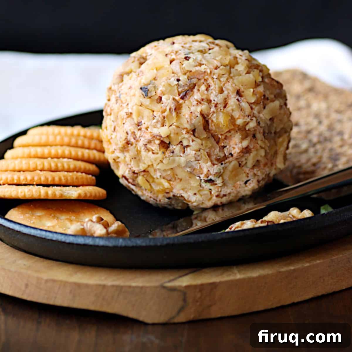Easy Cheddar Walnut Cheese Ball A homemade cheese ball with crackers on a serving platter.