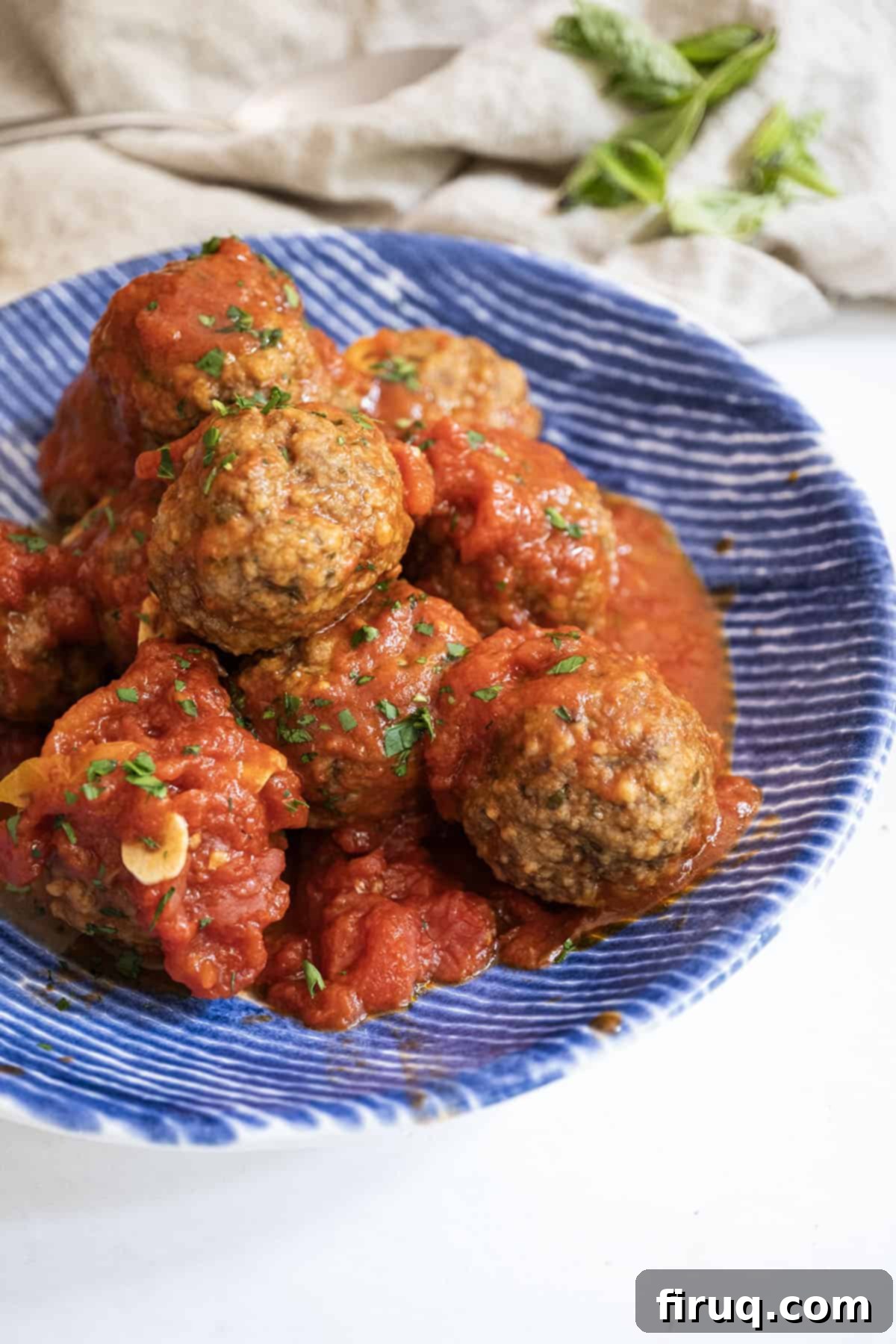 Nonna's Crispy Italian Meatballs 2 Meatballs covered in tomato sauce in a bowl.