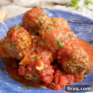 Nonna's Crispy Italian Meatballs 13 Meatballs covered in tomato sauce in a bowl.