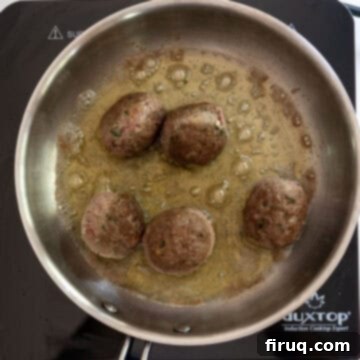 Nonna's Crispy Italian Meatballs 7 Meatballs browned while frying in a saucepan.