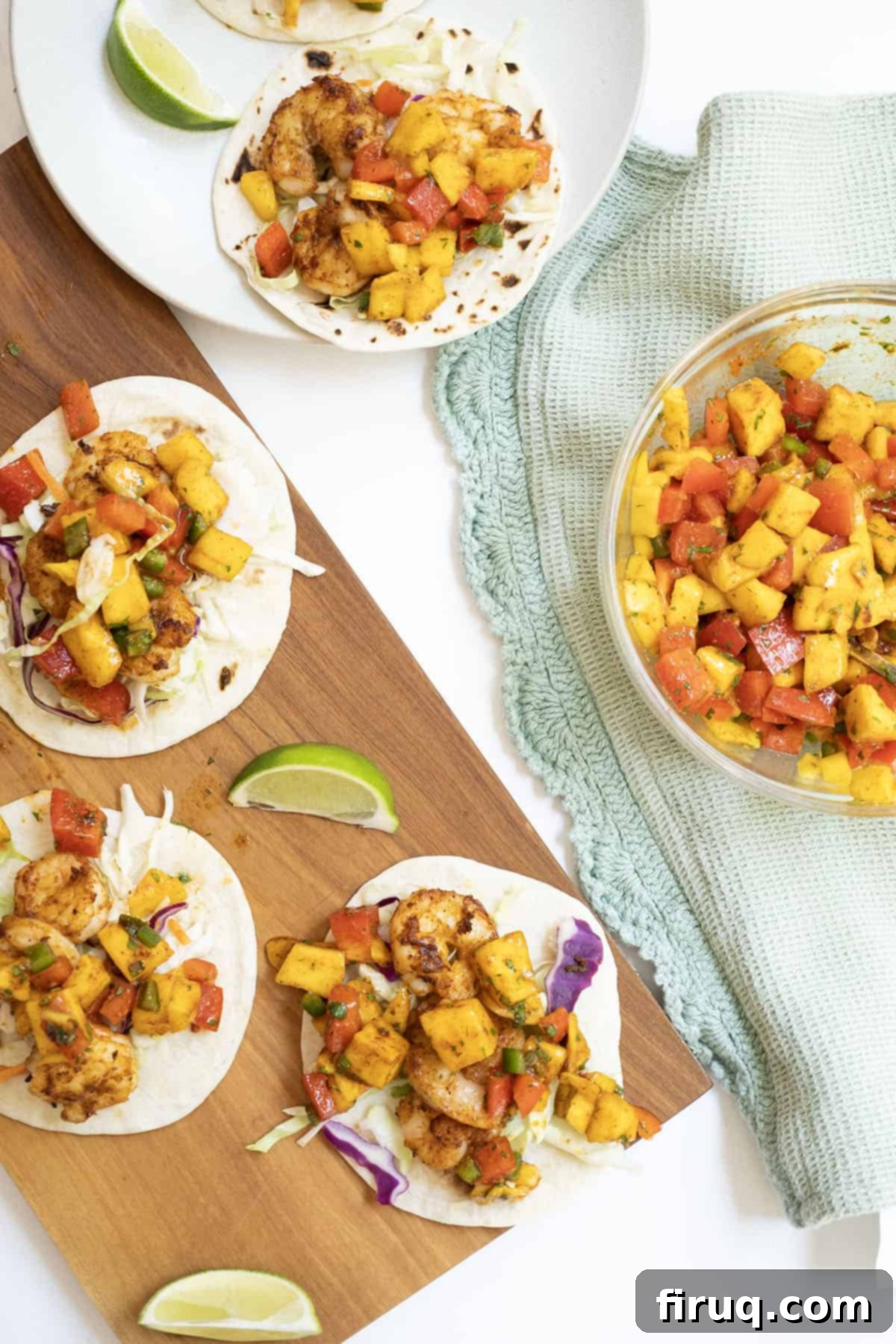 Tropical Shrimp Tacos with Mango Lime Zing 2 three shrimp tacos on white flour tortillas topped with mango salsa with a lime wedge in the middle.
