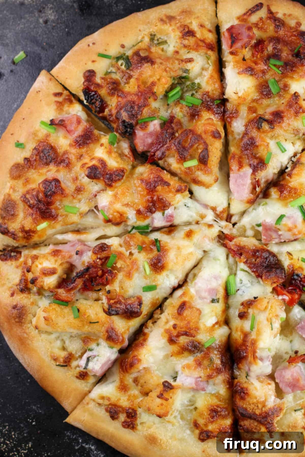 Chicken Cordon Bleu Pizza 9 sliced pizza on black pizza stone