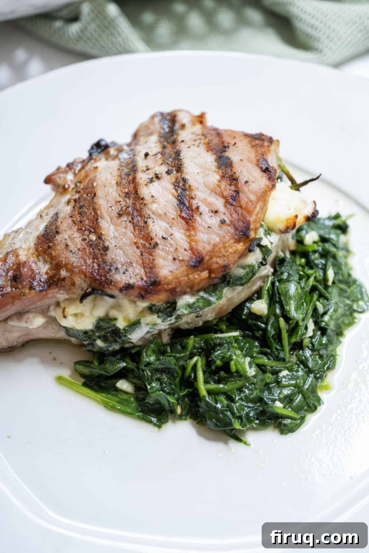 The Ultimate Grilled Stuffed Pork Chops 2 A perfectly grilled pork chop, butterflied and stuffed with a delicious mixture of melted feta cheese and vibrant sauteed spinach and garlic, elegantly served on a bed of fresh, tender spinach.