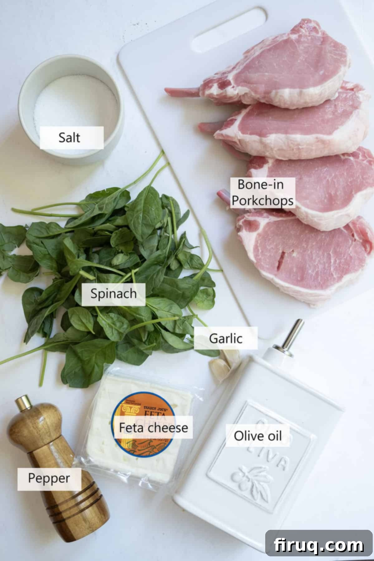 The Ultimate Grilled Stuffed Pork Chops 3 Fresh ingredients laid out for making grilled stuffed pork chops: block feta cheese, fresh spinach, bone-in pork chops, minced garlic, and a bottle of olive oil.