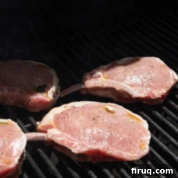 The Ultimate Grilled Stuffed Pork Chops 8 Seasoned and stuffed pork chops placed carefully on a hot grill, ready to cook and achieve perfect grill marks.