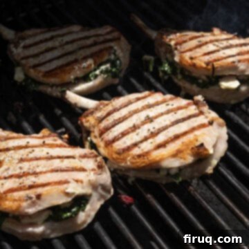 The Ultimate Grilled Stuffed Pork Chops 9 Grilled stuffed pork chops beautifully flipped on the grill, showcasing perfect sear marks and a golden-brown exterior, indicating they are nearly cooked through.