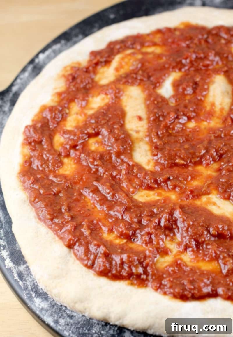Healthy Whole Wheat Pizza Dough 3 uncooked dough rolled out with a layer of sauce on top