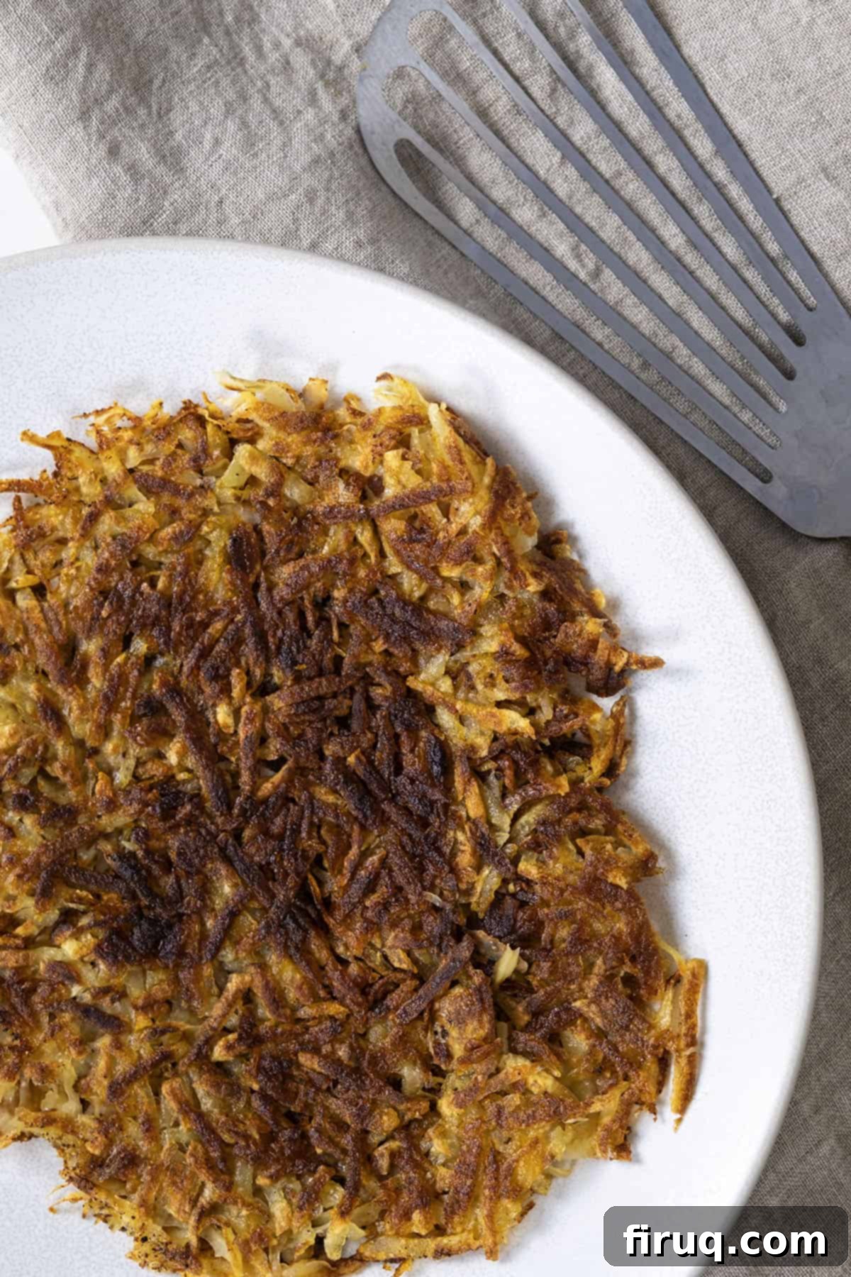 Crispy Hash Browns Perfection 11 A close-up of a serving of perfect, golden-brown crispy hash browns on a white plate, ready to be enjoyed.