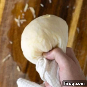 Crispy Hash Browns Perfection 7 Squeezing water out of grated potatoes wrapped in a cheesecloth.