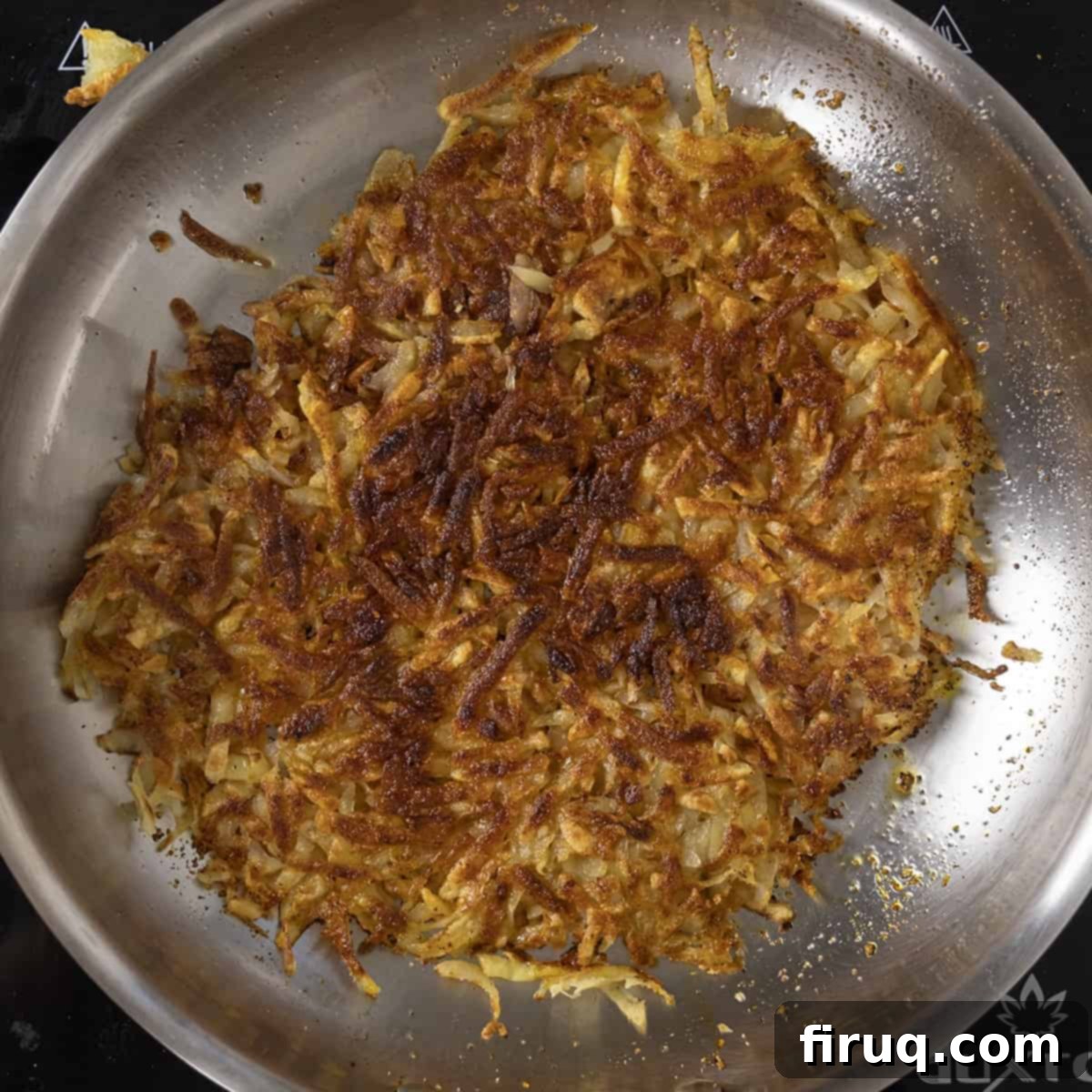 Crispy Hash Browns Perfection 10 Perfectly golden-brown and crispy hash browns, flipped and cooking on the second side in a frying pan.