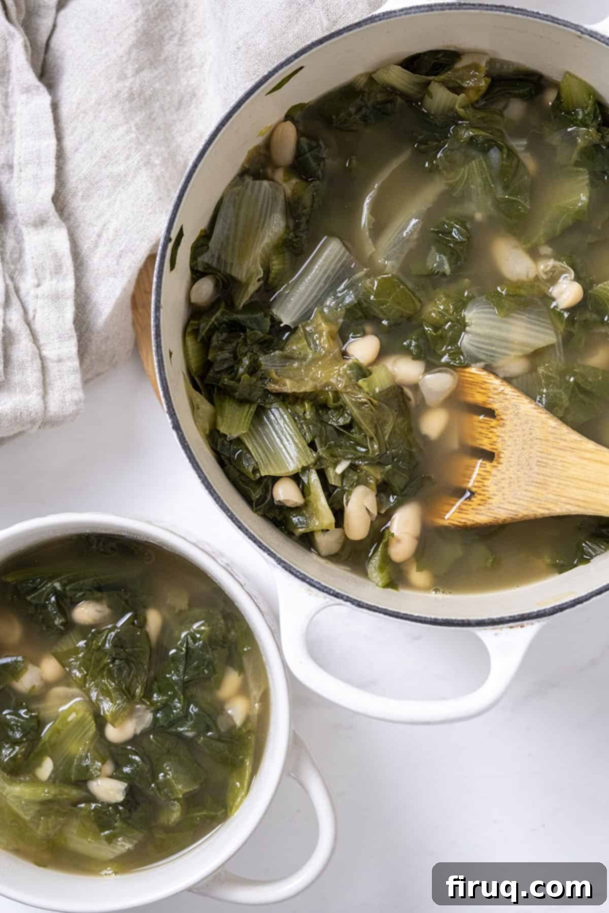 Hearty Escarole and Bean Soup 2 A rustic Dutch oven filled with bubbling escarole and bean soup, alongside a perfectly portioned bowl ready to be enjoyed. The vibrant green escarole and creamy white beans are clearly visible, promising a hearty, comforting meal.