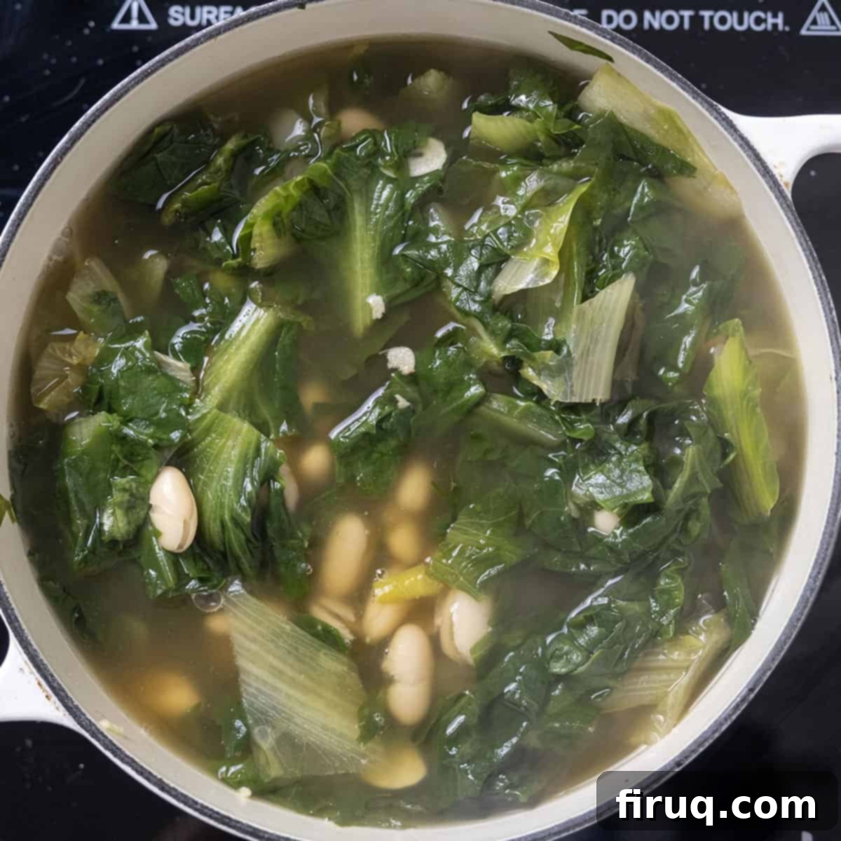 Hearty Escarole and Bean Soup 8 A Dutch oven filled with Escarole and Bean Soup, gently simmering on the stovetop, steam rising, indicating a warm and flavorful dish.