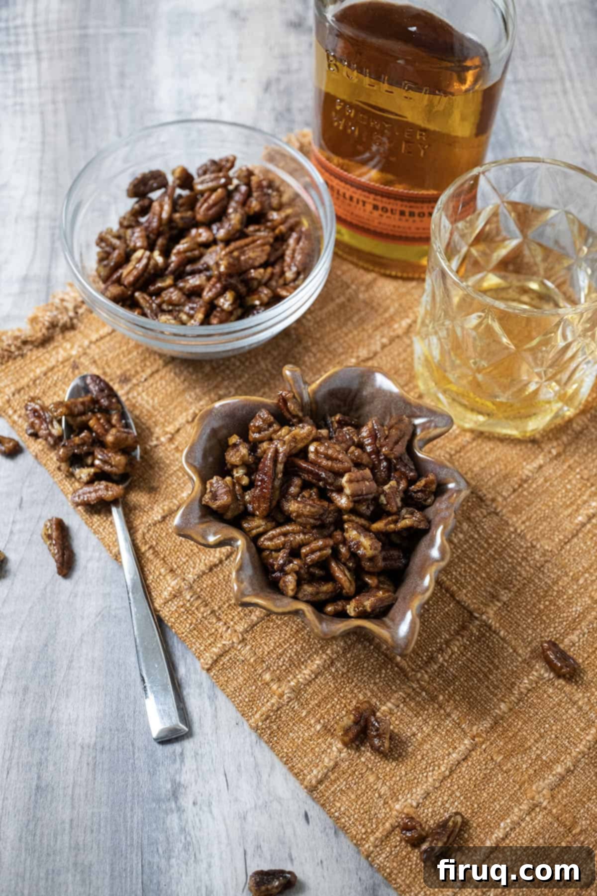 Decadent Bourbon Candied Pecans 2 Candied pecans in 2 separate bowls next to a glass of bourbon.