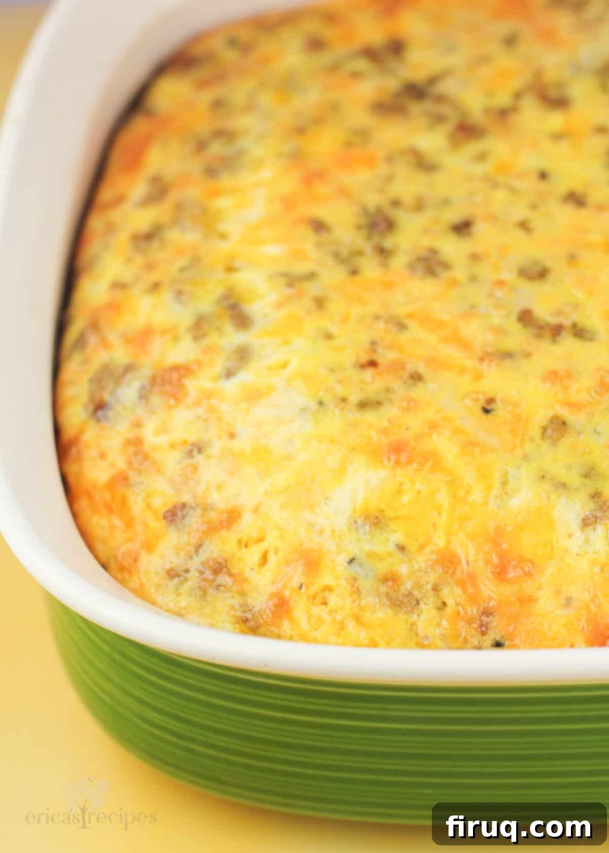 Hearty Sausage & Vegetable Bake 3 Close-up of a baked golden-brown sausage egg and cheese casserole in a vibrant green baking dish, showcasing its fluffy texture.