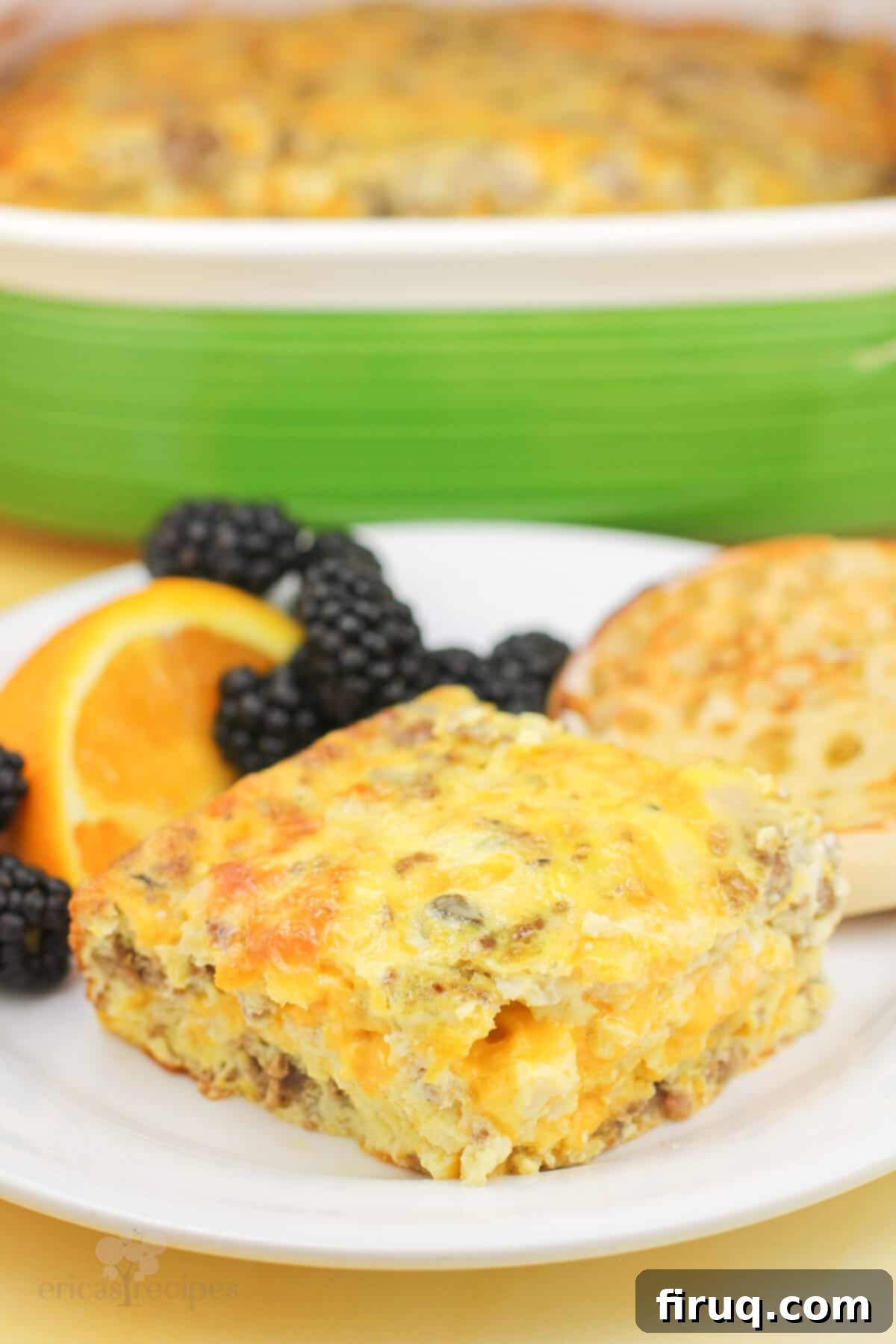 Hearty Sausage & Vegetable Bake 8 A close-up of a generous portion of sausage egg and cheese casserole on a white plate, beautifully garnished with fresh berries and orange slices.