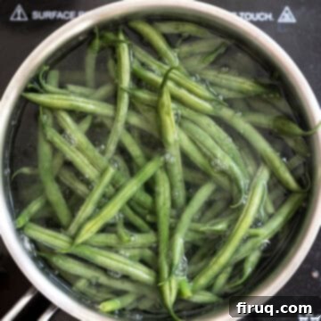 Mouthwatering Garlic Parmesan Green Beans 4 Green beans boiling vigorously in a pot of water on a stove.