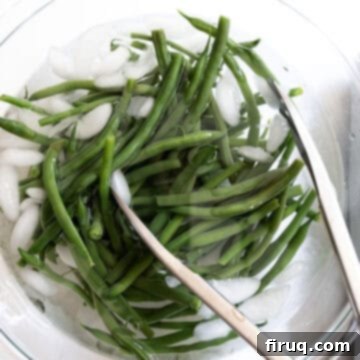 Mouthwatering Garlic Parmesan Green Beans 5 Blanched green beans submerged in a large bowl of ice water to stop the cooking process.