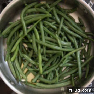 Mouthwatering Garlic Parmesan Green Beans 7 Blanched green beans added to a pan with sautéed garlic and olive oil, ready to be tossed.