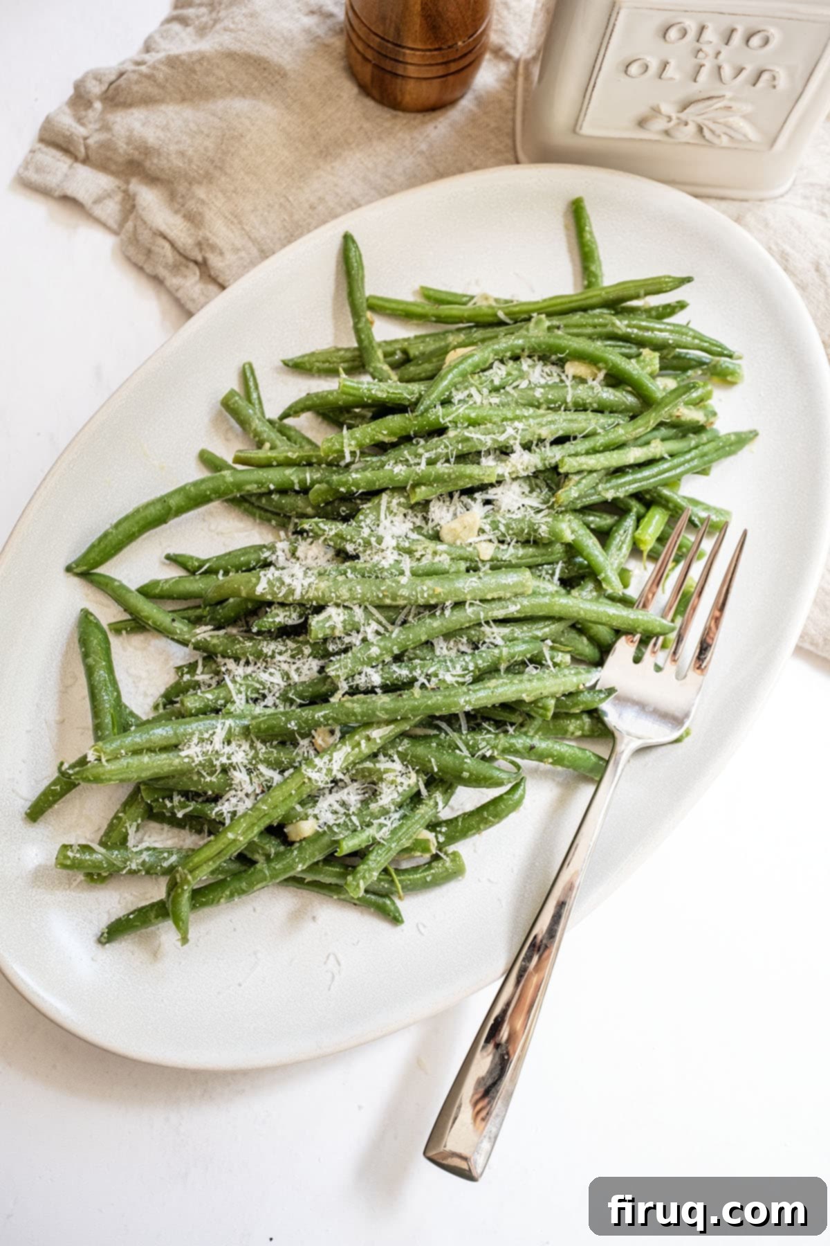 Mouthwatering Garlic Parmesan Green Beans 9 Close-up of vibrant sautéed green beans with sliced garlic and a generous sprinkling of Parmesan cheese on a white plate.
