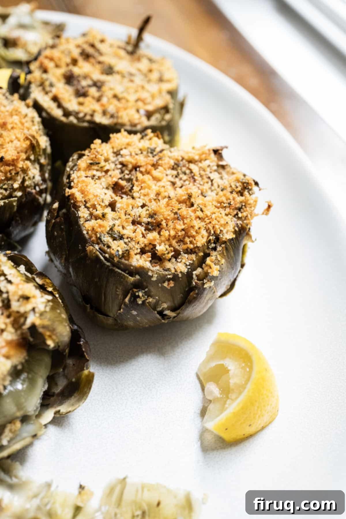 Simple Italian Stuffed Artichokes 2 Stuffed artichokes on a plate with lemon.