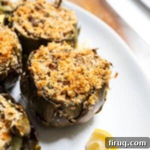 Simple Italian Stuffed Artichokes 11 Stuffed artichokes on a plate with lemon.