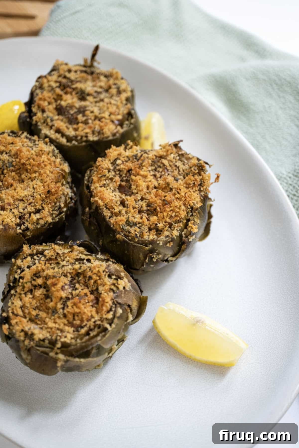 Simple Italian Stuffed Artichokes 10 Stuffed artichokes on a plate with lemon.