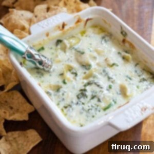 Guilt-Free Creamy Spinach Artichoke Dip 8 Spinach and artichoke dip in a dish with some tortilla chips next to it.