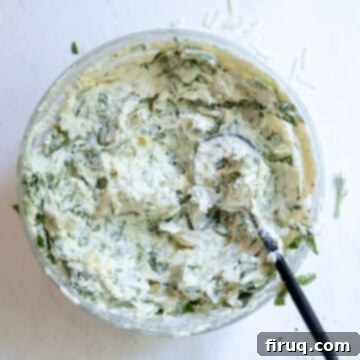 Guilt-Free Creamy Spinach Artichoke Dip 5 Cheese mixed with spinach and artichokes in a bowl.
