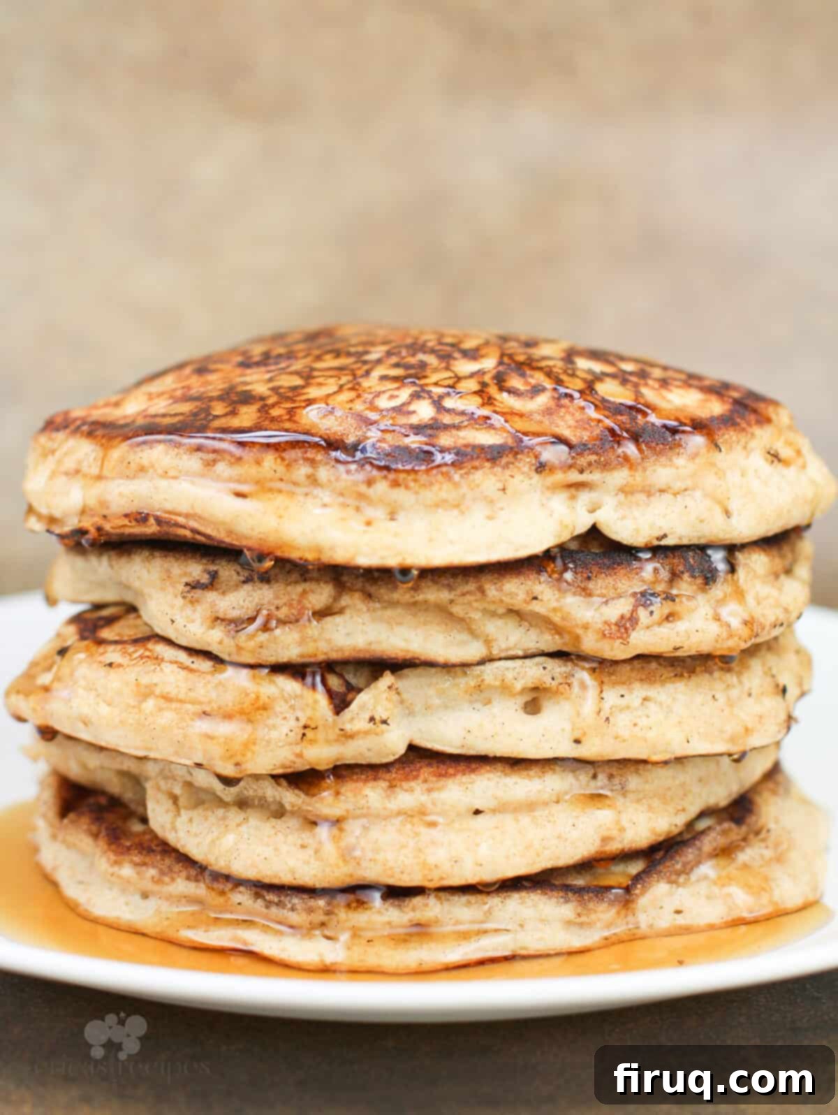 Fluffy Cinnamon Applesauce Pancakes 3 pancakes dripping with syrup stacked on white plate, side view