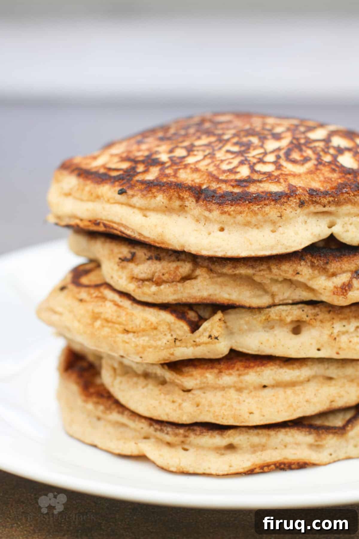 Fluffy Cinnamon Applesauce Pancakes 8 pancakes stacked on white plate, side view