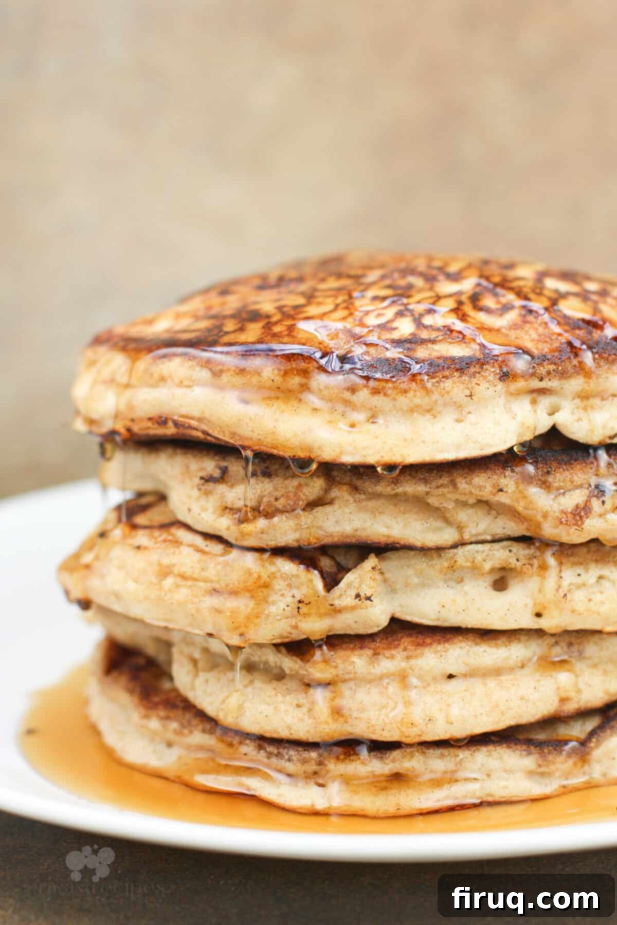 Fluffy Cinnamon Applesauce Pancakes 10 pancakes dripping with syrup stacked on white plate, side view