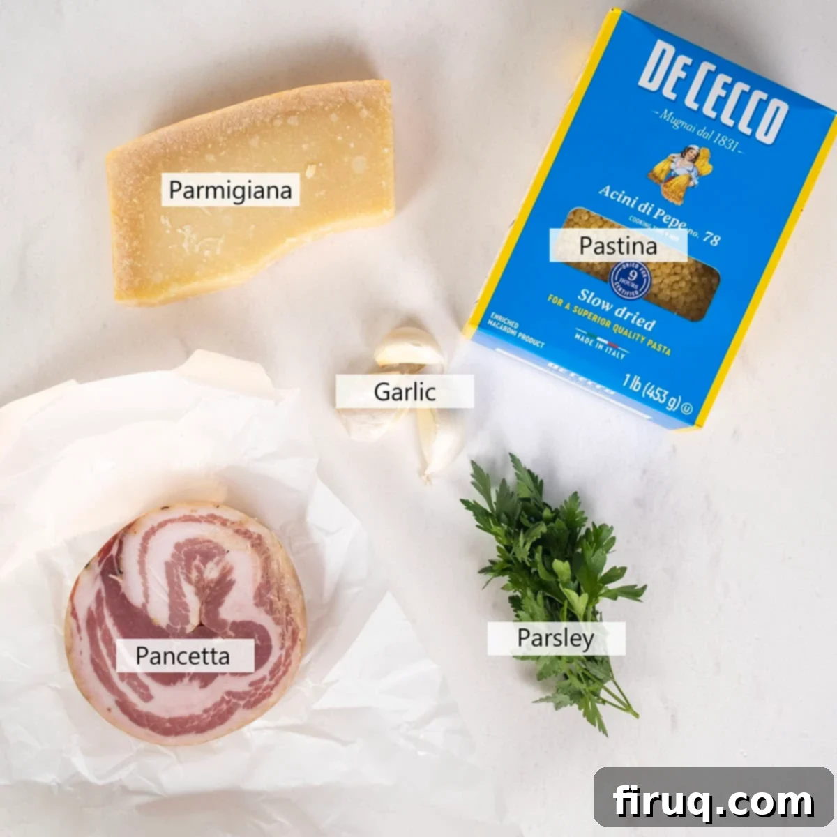 Classic Pastina Carbonara 3 Various ingredients laid out for Creamy Pastina Carbonara, including pancetta, pastina, garlic, and a block of Parmigiano cheese.