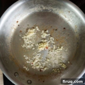 Classic Pastina Carbonara 8 Minced garlic being sautéed in a pan with residual pancetta fat.